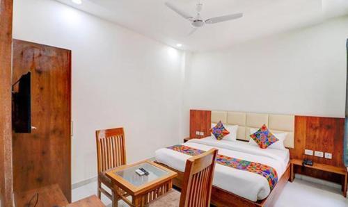 勒克瑙FabExpress Pravi Inn的一间卧室配有一张床、一张桌子和一张桌子