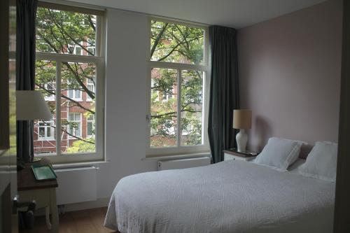 阿姆斯特丹阿姆斯特丹大公寓的卧室配有白色的床和2扇窗户。