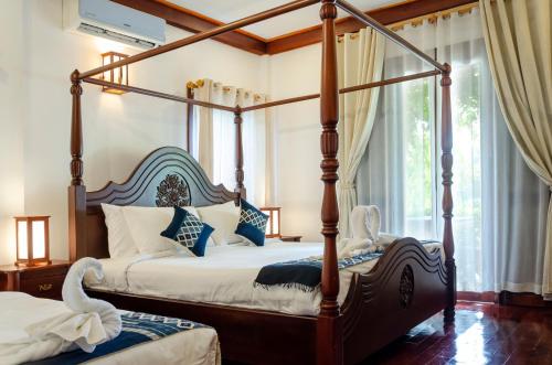 琅勃拉邦Villa Khili Namkhan的一间卧室设有四柱床和窗户。