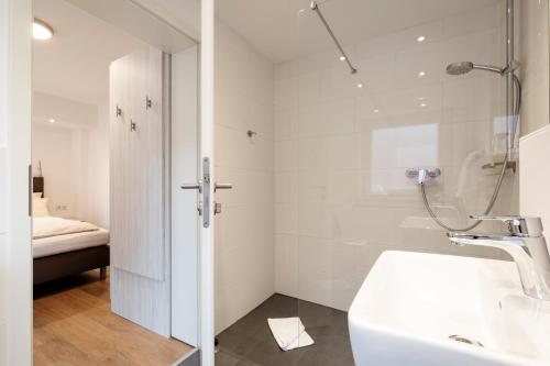 黑尔戈兰岛Hotel Felsen-Eck的带淋浴和盥洗盆的白色浴室