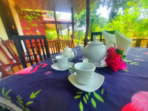 达瓦拉维Elephants Safari Cottages的一张桌子,上面有紫色的桌布和茶具