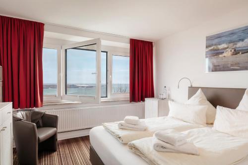 黑尔戈兰岛Hotel Felsen-Eck的一间卧室配有一张床、一把椅子和窗户。
