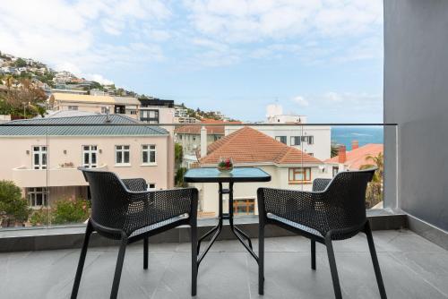 开普敦Ocean & Mountain Views From Bantry Bay Apartment的阳台的天井配有2把椅子和1张桌子