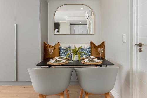 开普敦Ocean & Mountain Views From Bantry Bay Apartment的餐桌,配有两把白色椅子和镜子