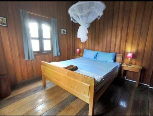 邦隆Ratanakiri Lakeside Homestay & Tours的木制客房的一张床位,设有窗户