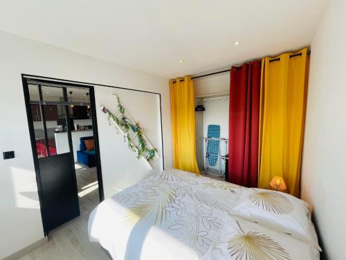 加来La Brise Marine的一间卧室配有色彩缤纷的窗帘和一张床