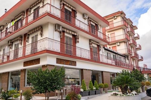 庞特卡格纳诺HOTEL 1+1 di C.Costabile & f.lli的公寓大楼设有红色的阳台和树木