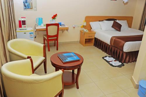RwamaganaDereva Hotel Rwamagana的酒店客房带一张床、一张桌子和椅子