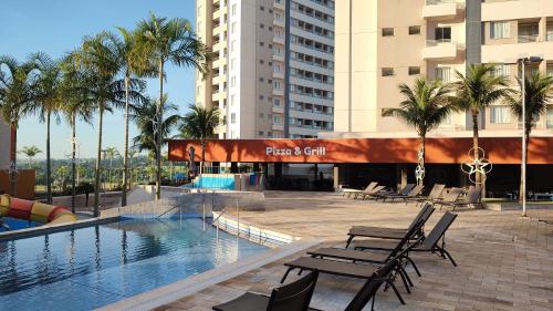 奥林匹亚Solar das Águas - Resort Em Olimpia - Ap 2 quartos的一座游泳池,里面摆放着椅子和棕榈树