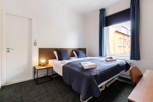 欧登塞Milling Hotel Mini 19的一间卧室配有一张带蓝色床单的床和一扇窗户。