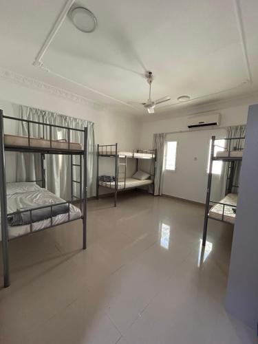 马斯喀特Basil Hostel的一间带三张双层床的房间和一间带走廊的房间