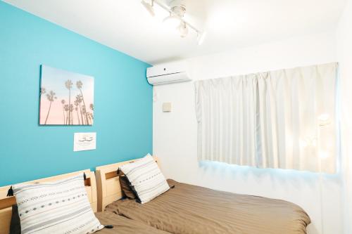 恩纳Base in Onnason,Okinanawa ウォータサーバー,本格コーヒー,アメニティと設備充実,ベビー用品,おもちゃ完備,BBQ可能的一间卧室设有一张床和蓝色的墙壁