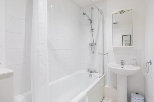 剑桥Lovely 2 bedroom apartment - ideal location的白色的浴室设有水槽、浴缸和淋浴。