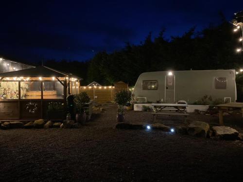 霍利韦尔Top Pen Y Parc Farm Glamping的夜间在院子里放拖车和帐篷