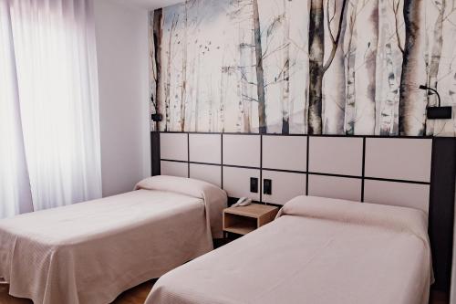 比利亚罗夫莱多卡萨洛伦佐酒店的墙上树木间内的两张床