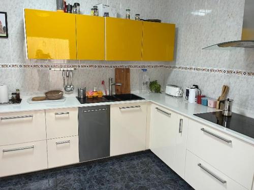 SooSunset house的厨房配有白色的柜台和黄色的橱柜