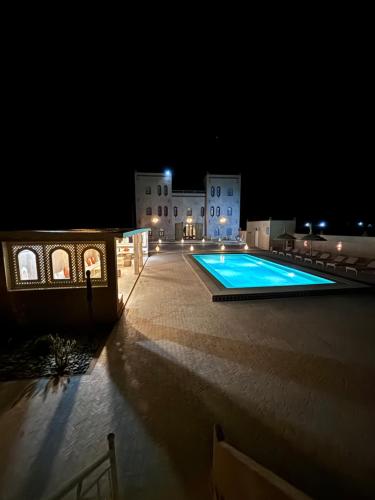 梅尔祖卡Dar Morocco的一座游泳池,在晚上在建筑物前