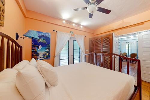 珀拉什奇亚Condo #24 @ Beachside Villas的一间卧室配有一张带吊扇和窗户的床。