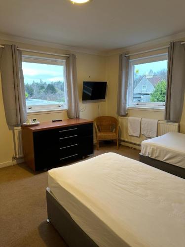 金罗斯The Kinross Salutation Hotel的一间卧室配有两张床、一张桌子和两个窗户。