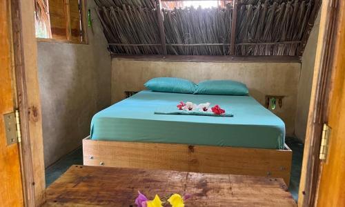 帕洛米诺La Aldea Hostel, Camping y Hamacas的一间卧室配有一张蓝色床单和鲜花的床。