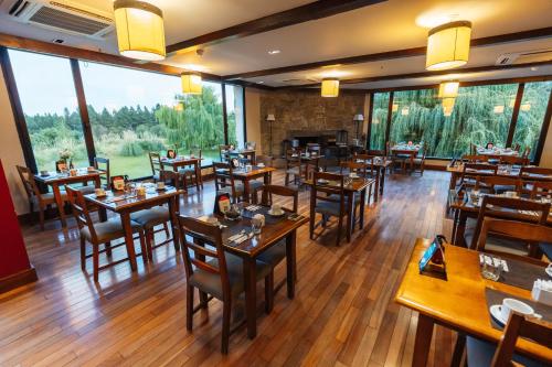 圣马丁德洛斯夏佩克套房酒店的餐厅设有木桌和椅子以及大窗户。