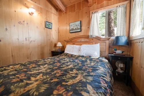 方斯金Owl Cabin - Sierra style cabin located on a quiet road in Fawnskin and backs up to National Forest!的木制客房内的一间卧室,配有一张床