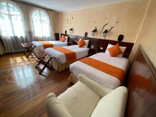 基多Kitu Hotel的酒店客房,设有三张床和一张沙发