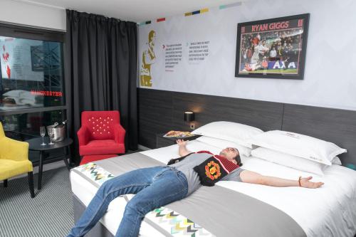 曼彻斯特Hotel Football, Old Trafford, a Tribute Portfolio Hotel的躺在床上吃比萨饼的人