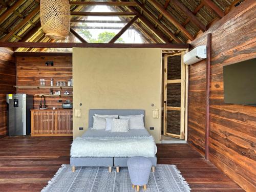 洛斯纳兰霍斯Cabaña Vista al Mar Tayrona, A/C的卧室配有一张床铺,位于带木墙的房间内