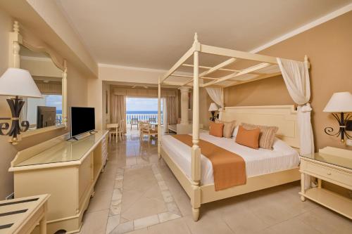 拉纳韦贝Bahia Principe Luxury Runaway Bay - Adults Only All Inclusive的一间卧室配有一张天蓬床和一台电视机