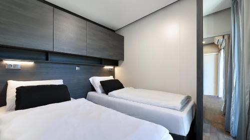 塞尔瑟Adrialux Camping Mobile Homes的一间卧室配有两张带白色床单的床