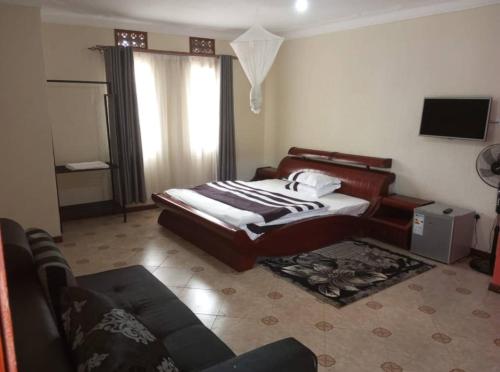 恩德培Migingo Suites的一间卧室配有一张床、一张沙发和一台电视