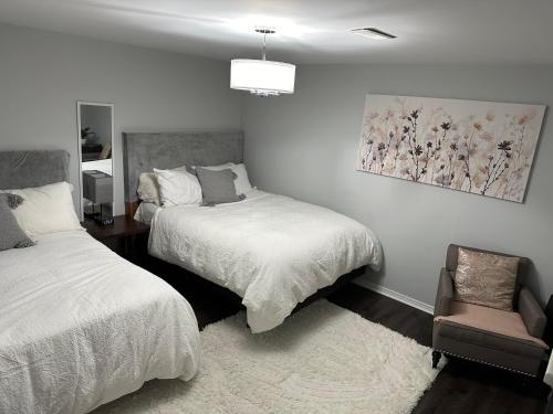 布兰普顿Luxurious and modern one bedroom basement suite.的一间卧室配有两张床和椅子