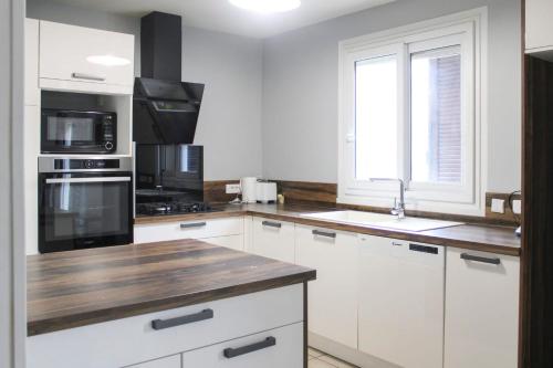 圣但尼Cozy and spacious house in Saint-Denis的厨房配有白色橱柜和木制台面