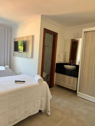 阿拉亚尔达茹达Casa em Arraial d'Ajuda的一间卧室配有一张床,浴室设有水槽