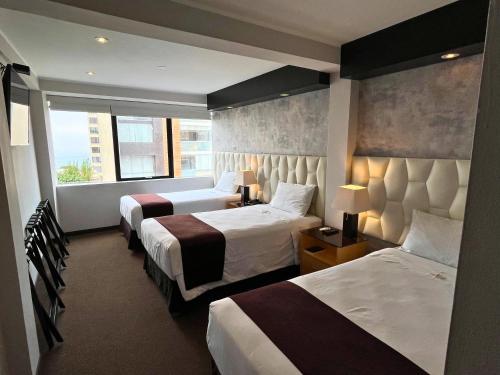 利马Hotel Ferre Miraflores的酒店客房设有两张床和窗户。