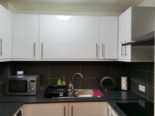 威灵堡Newly Renovated Cosy 1 bed flat, 4 minutes walk to Town Centre, 3 minutes walk to the train station, Free parking, Modern, fresh and spacious living room, Netflix ready smart TV, Wifi的厨房配有白色橱柜、水槽和微波炉