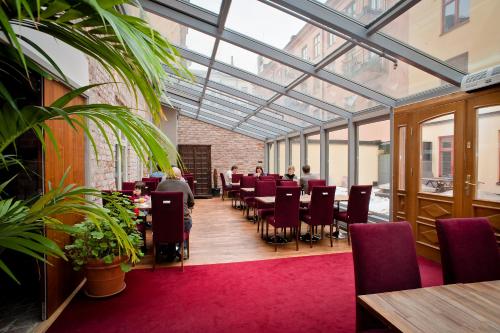 斯德哥尔摩雷克斯佩蒂特酒店的一个带桌椅的温室,以及坐在桌子旁的人