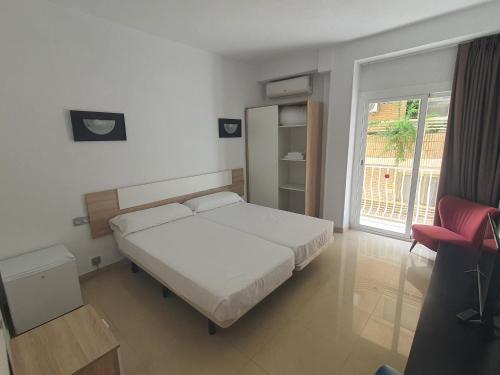 贝尼多姆Hotel Molí Beach的卧室配有白色的床和红色椅子