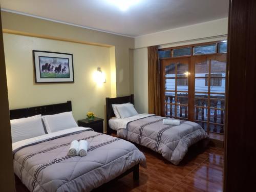 奥克萨潘帕Hospedaje "LOS QUETZALES DE OXAPAMPA"的酒店客房设有两张床和窗户。