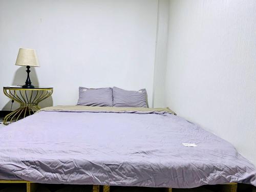 胡志明市SÀI GÒN INN ĐỀ THÁM的一间卧室配有一张带紫色床单和灯的床