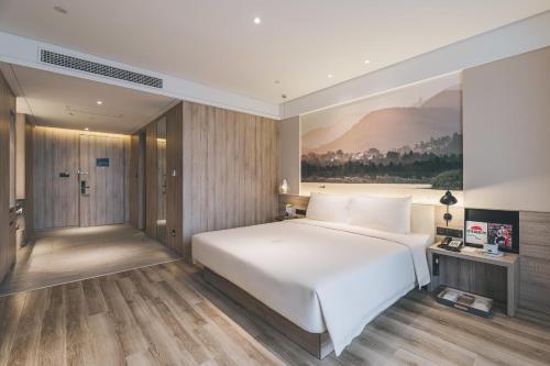 南京南京南站亚朵酒店的卧室配有白色的床和墙上的绘画作品