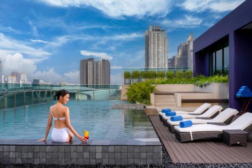 曼谷曼谷麦卡桑美居酒店的站在游泳池旁的比基尼的女人