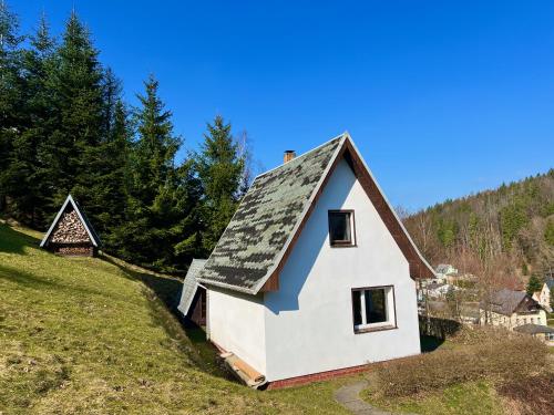 PobershauUrige Berghütte mit Kamin in Pobershau im Erzgebirge nahe Schwarzwassertal的山坡上白色的房子,屋顶黑色