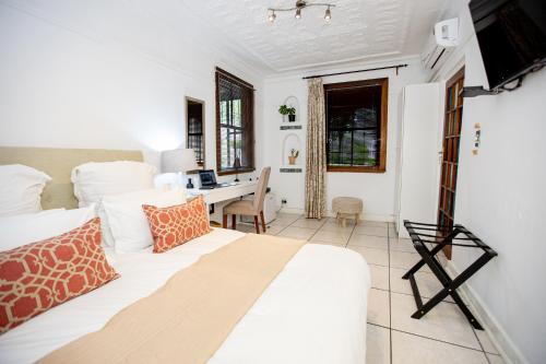 约翰内斯堡84第四号旅馆的卧室配有白色的床和书桌