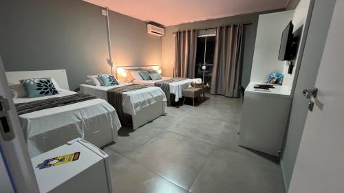 佩尼亚Pousada da Bia Praia的酒店客房设有两张床和电视。