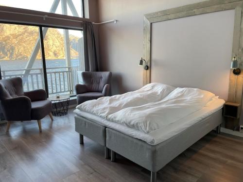 HamnaVærlandet Havhotell的一间卧室配有一张床、两把椅子和一个窗户