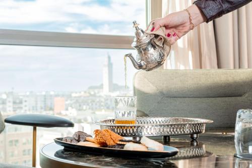 卡萨布兰卡伊杜安法Spa酒店的把茶壶放在桌子上的人,带食物