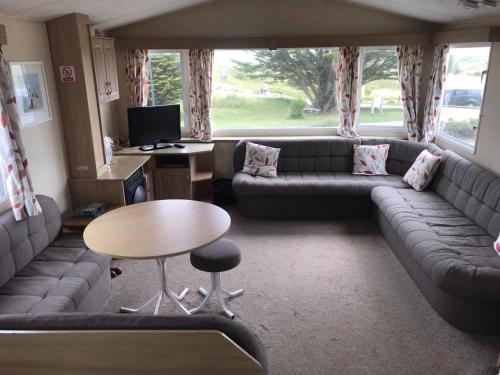 佩伦波斯6-8 berth caravan, Perran Sands Haven Holiday Park, Cornwall的客厅配有沙发和桌子