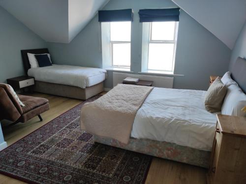 班多伦4 Bayview terrace的一间卧室配有一张床和一把椅子,还有两个窗户